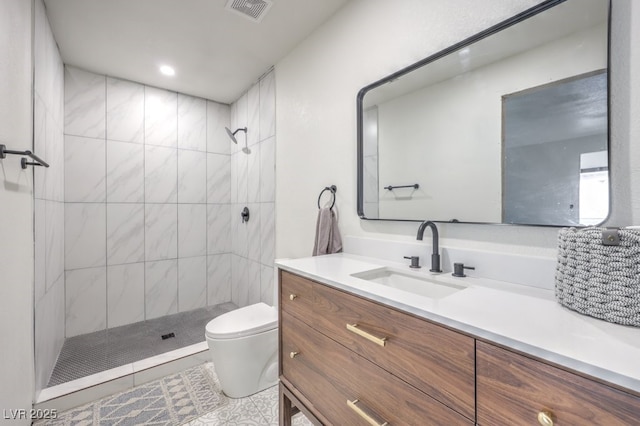 bathroom featuring visible vents, tiled shower, toilet, and vanity