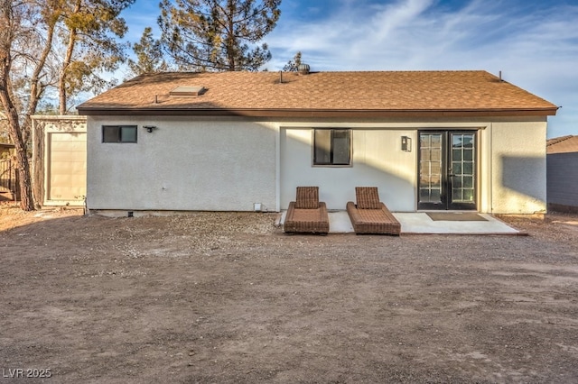 back of house with stucco siding, roof with shingles, and a patio area
