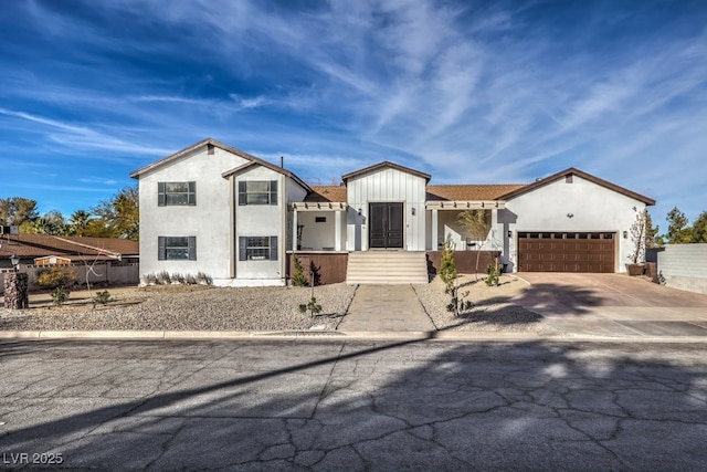 view of front of home featuring driveway, fence, stucco siding, and an attached garage