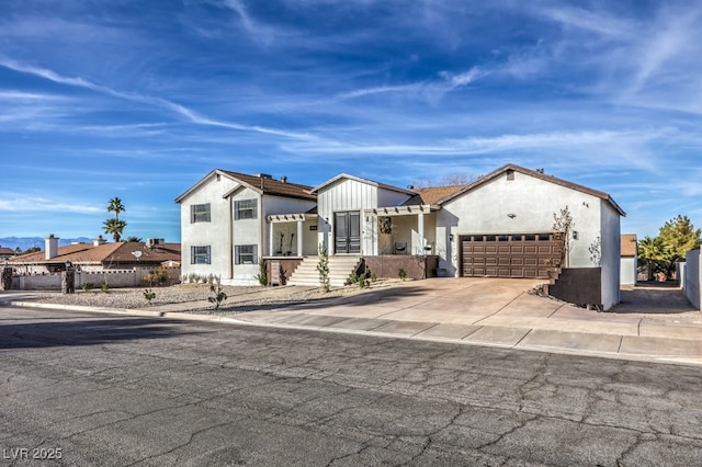 view of front of house with driveway, fence, stucco siding, and an attached garage