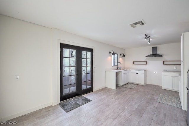 interior space with a sink, light wood-style floors, visible vents, baseboards, and french doors
