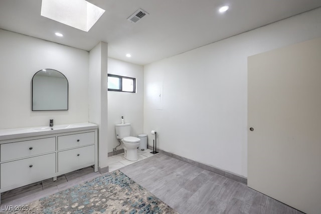 bathroom featuring recessed lighting, vanity, toilet, visible vents, and a skylight