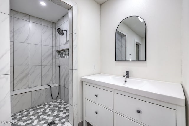 full bathroom with tiled shower and vanity