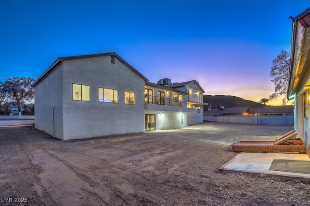 back of property with fence, stucco siding, and a balcony