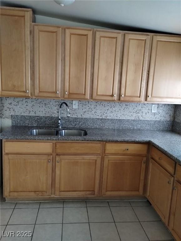 kitchen featuring light tile patterned flooring, a sink, backsplash, and light brown cabinets