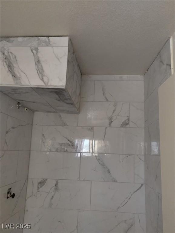 full bath with a tile shower and a textured ceiling
