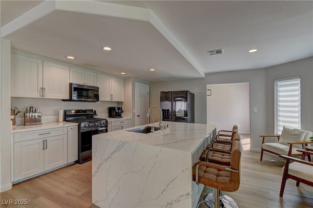 kitchen with visible vents, appliances with stainless steel finishes, light wood finished floors, and a sink