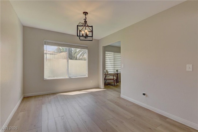 unfurnished dining area with wood finished floors, a chandelier, and baseboards