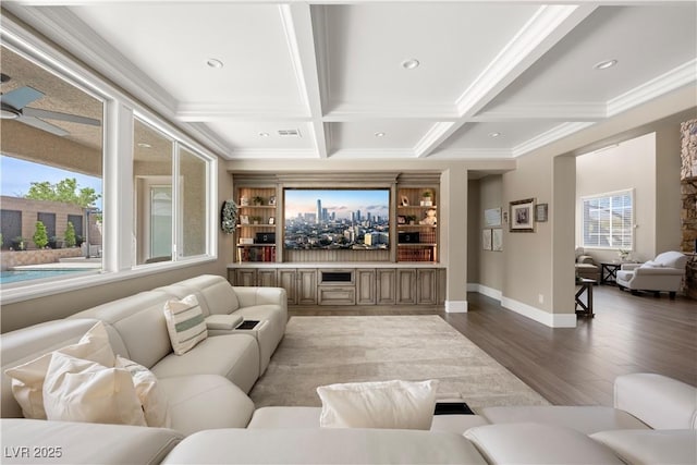 cinema with beam ceiling, baseboards, wood finished floors, and crown molding