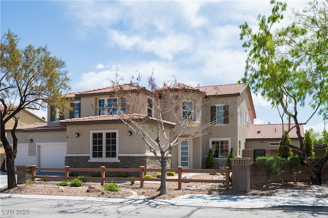 mediterranean / spanish-style house with stucco siding, a tile roof, a fenced front yard, and stone siding