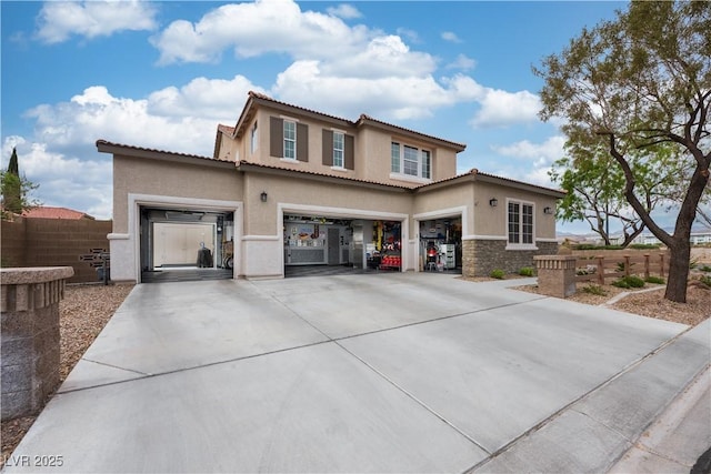 view of front of house with fence, concrete driveway, stone siding, stucco siding, and a garage