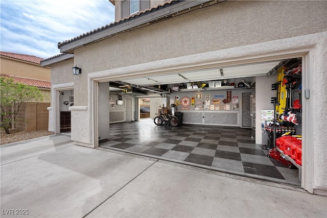 garage featuring fence and concrete driveway
