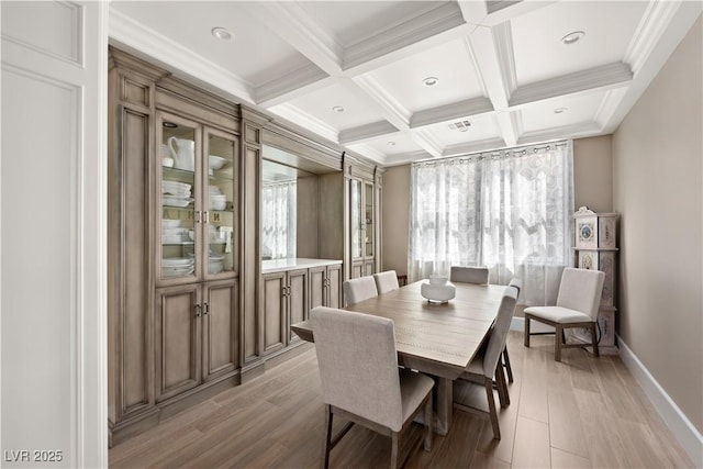 dining space with coffered ceiling, a healthy amount of sunlight, beam ceiling, and baseboards