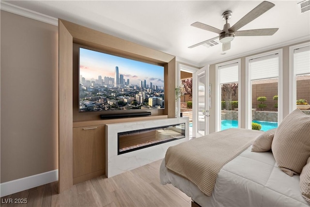 bedroom featuring light wood-style flooring, visible vents, access to exterior, a glass covered fireplace, and a ceiling fan