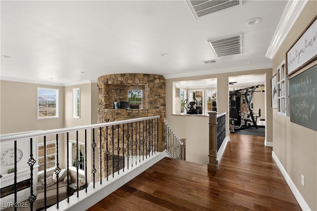 corridor with ornamental molding, an upstairs landing, visible vents, and wood finished floors