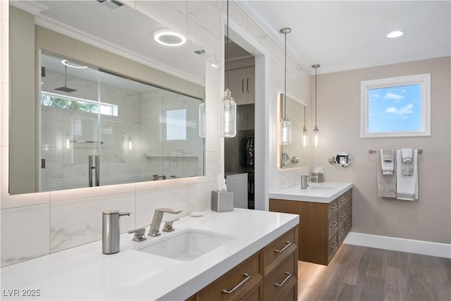 full bath with a shower stall, crown molding, a sink, baseboards, and wood finished floors