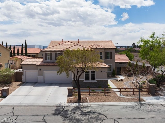 mediterranean / spanish home featuring stucco siding, fence, a tile roof, driveway, and stone siding