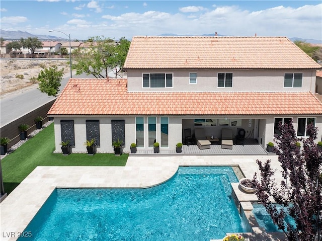 rear view of property with stucco siding, a patio area, and a tile roof