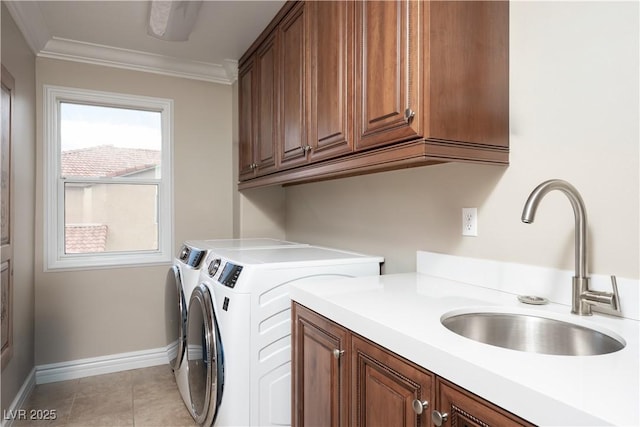 laundry room with a sink, baseboards, washer and clothes dryer, ornamental molding, and cabinet space