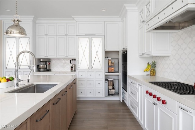 kitchen with under cabinet range hood, white cabinets, dark wood-style flooring, a sink, and stovetop