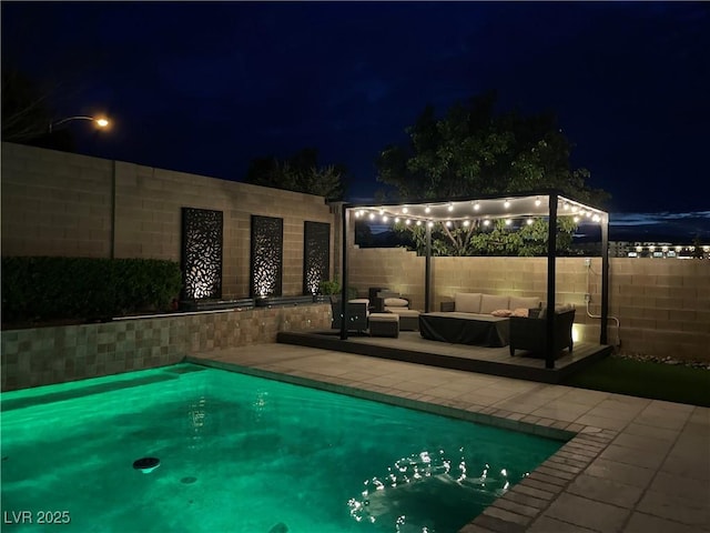 pool at night featuring a fenced in pool, a patio area, an outdoor hangout area, and a fenced backyard