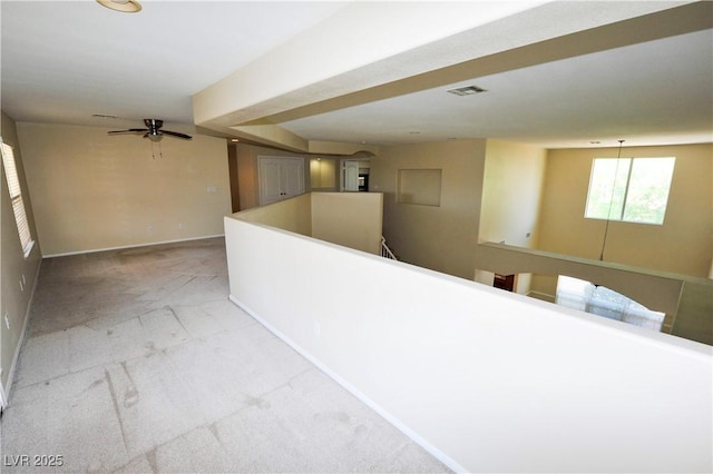 hall with an upstairs landing, visible vents, light carpet, and baseboards