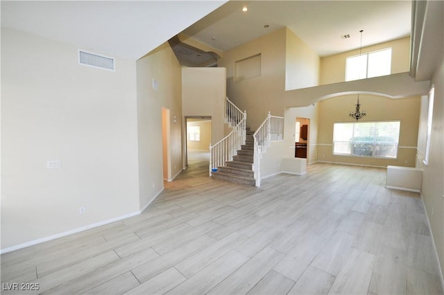 unfurnished living room featuring a high ceiling, visible vents, and light wood-style floors
