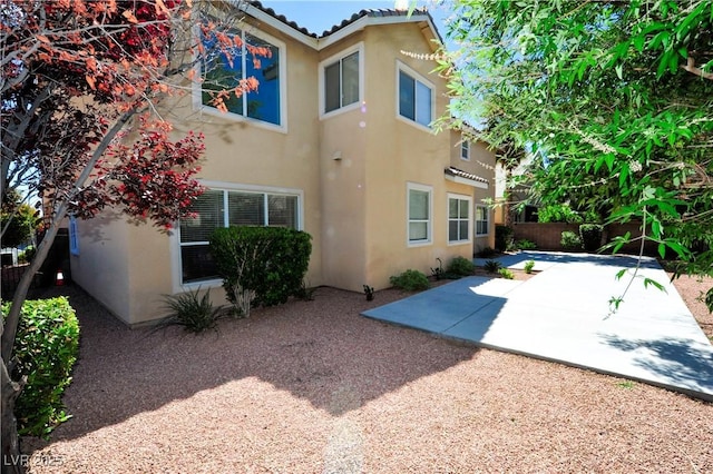 back of property with fence, stucco siding, and a patio area
