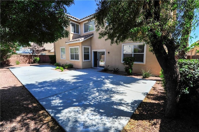back of house with a tile roof, a patio, stucco siding, and a fenced backyard