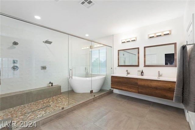 bathroom featuring a stall shower, double vanity, tile patterned floors, a freestanding tub, and recessed lighting