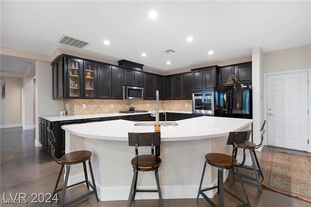 kitchen featuring appliances with stainless steel finishes, decorative backsplash, a sink, an island with sink, and recessed lighting