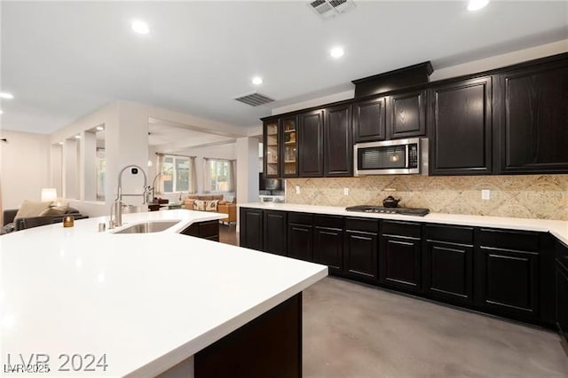 kitchen featuring stainless steel appliances, open floor plan, a sink, decorative backsplash, and recessed lighting