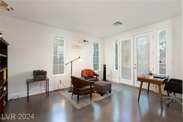 living area featuring french doors, concrete floors, and baseboards