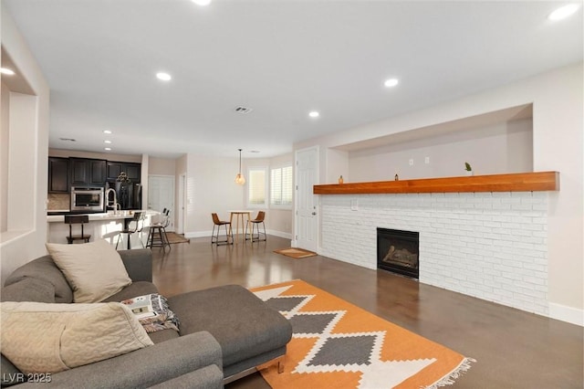 living room featuring baseboards, recessed lighting, and a brick fireplace