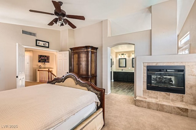 13 Cozy Glen Cir, Henderson, NV 89074 - carpeted bedroom with connected bathroom, a high ceiling, a sink, a tile fireplace, and visible vents