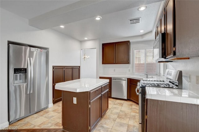 8236 Bermuda Beach Dr, Las Vegas, NV 89128 - kitchen with visible vents, tile counters, a center island, a sink, and appliances with stainless steel finishes