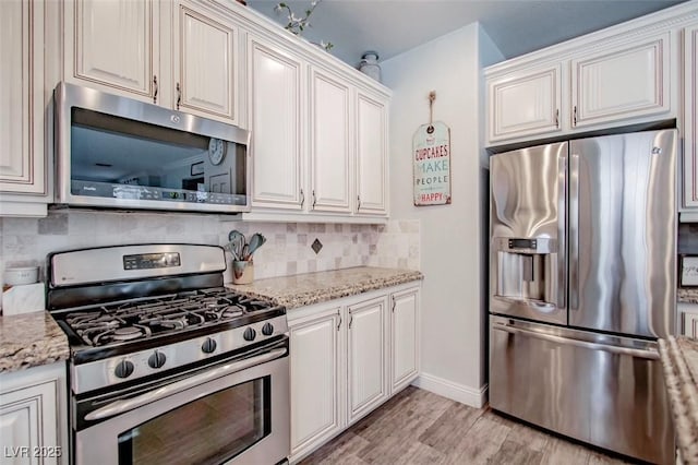 1125 Via Canale Dr, Henderson, NV 89011 - kitchen with light stone counters, appliances with stainless steel finishes, decorative backsplash, and light wood-type flooring