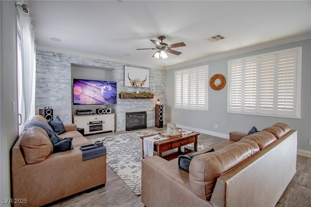 1125 Via Canale Dr, Henderson, NV 89011 - living area featuring wood finished floors, ornamental molding, ceiling fan, a fireplace, and visible vents