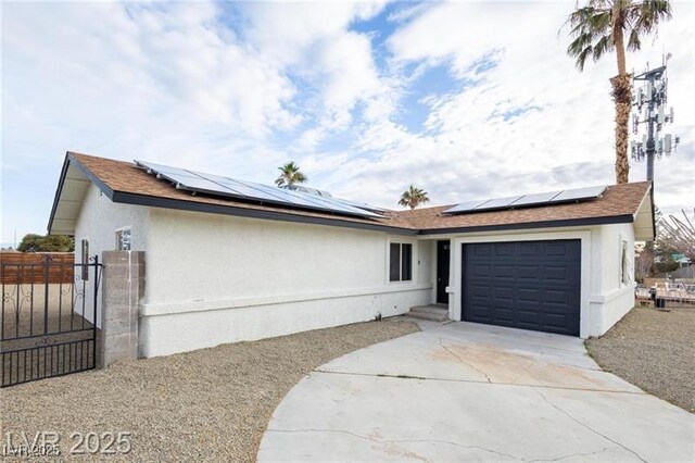 view of front of house featuring stucco siding, a gate, solar panels, concrete driveway, and an attached garage