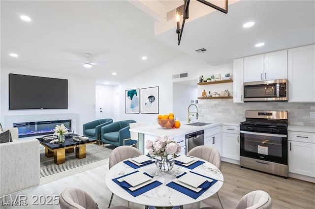kitchen featuring decorative backsplash, a sink, appliances with stainless steel finishes, visible vents, and light wood-style floors