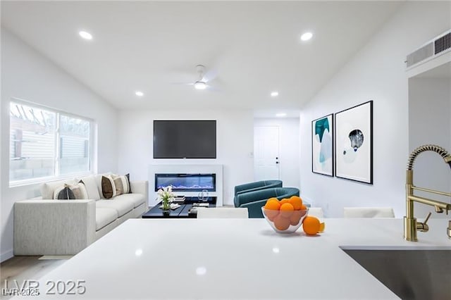 living area with wood finished floors, recessed lighting, a ceiling fan, and baseboards