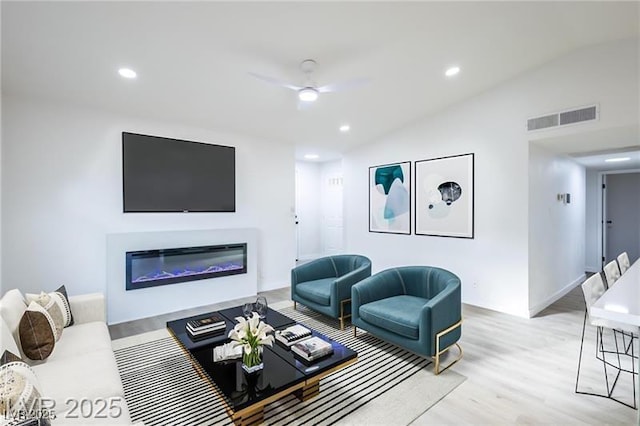 living room featuring recessed lighting, a glass covered fireplace, a ceiling fan, visible vents, and wood finished floors