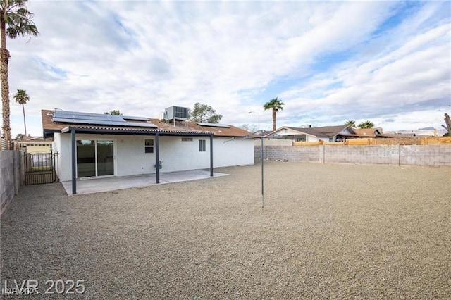 rear view of property featuring a patio area, a fenced backyard, a gate, central AC, and roof mounted solar panels