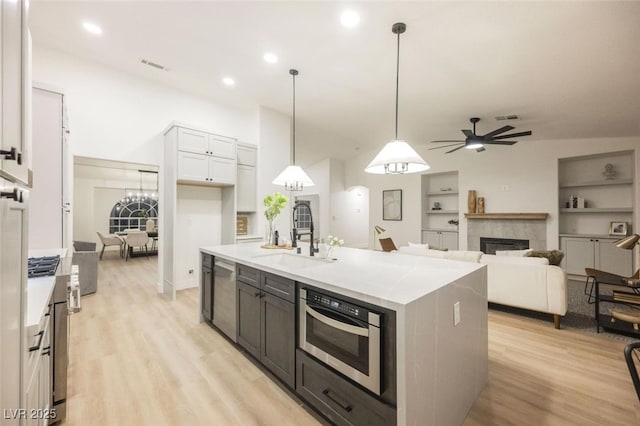 kitchen featuring stainless steel dishwasher, a sink, visible vents, light wood finished floors, and a ceiling fan