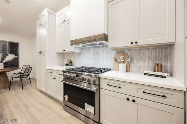 kitchen featuring high end stainless steel range, custom range hood, and light countertops