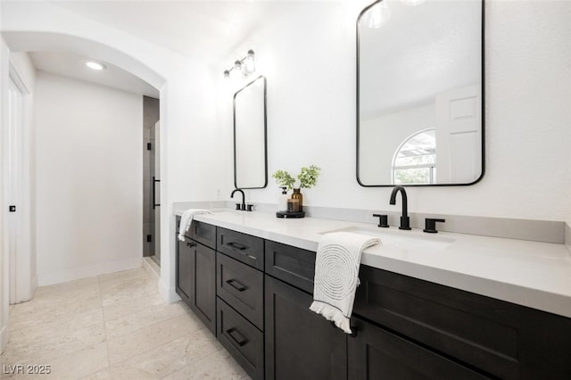 bathroom with double vanity, baseboards, a stall shower, and a sink