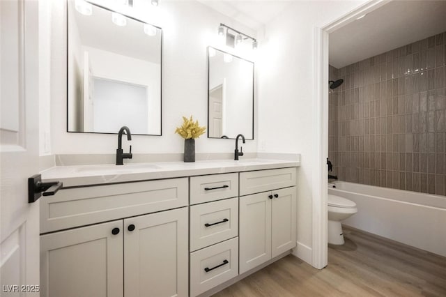 bathroom with toilet, double vanity, a sink, and wood finished floors