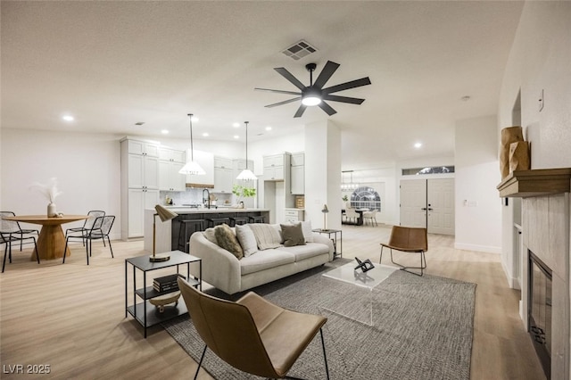 living room with recessed lighting, a tile fireplace, light wood-style floors, a ceiling fan, and visible vents