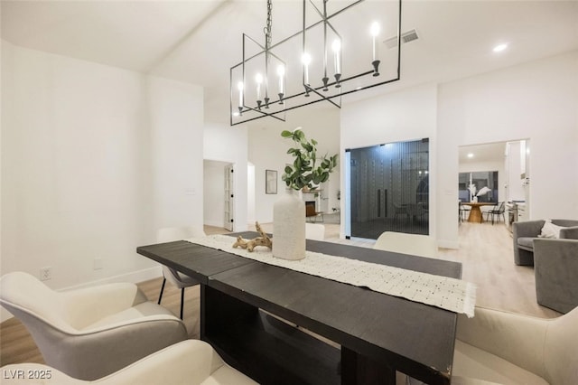 dining space featuring visible vents, baseboards, recessed lighting, a towering ceiling, and wood finished floors