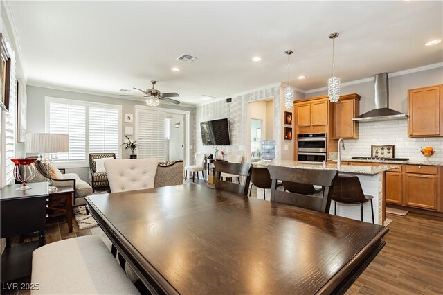 dining room featuring wood finished floors, visible vents, a ceiling fan, and ornamental molding